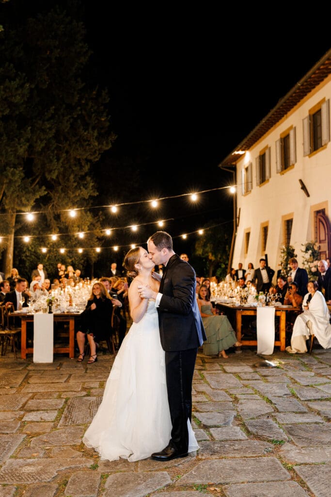 First dance on the stone courtyard under string lights