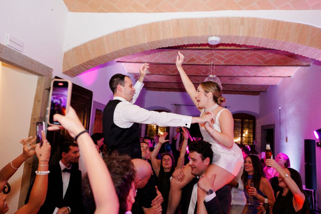 Hannah in her second dress lifted on a guest's shoulders on the dance floor