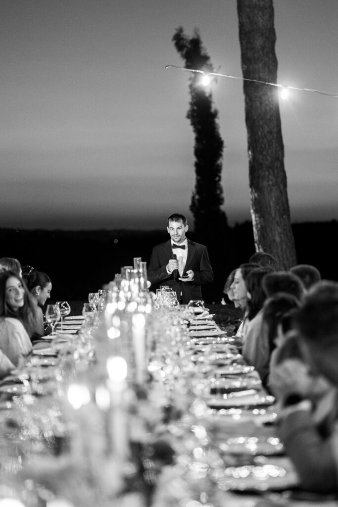 Guest giving a speech at the candlelit wedding dinner, black and white
