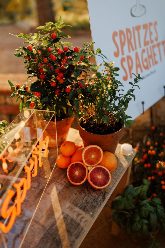 Spritzes and Spaghetti welcome party sign with blood oranges and terracotta pots at a Tuscany destination wedding