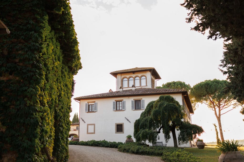 Exterior of Tenuta di Sticciano wedding venue near Certaldo, Tuscany, with manicured gardens, terracotta urns, and a classic Tuscan villa facade